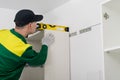 A worker checks the evenness of the installation of the upper cabinet of the kitchen unit, close-up