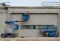 A worker on a cherry picker finishes the newly constructed facade of a new building. On the right an aerial platform