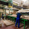 Worker with circular saw machine at wood beam cross cutting during furniture manufacture