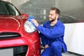 Worker cleaning automobile headlight with rag