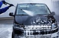 Worker cleaning automobile with high pressure water jet at car wash Royalty Free Stock Photo