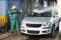 Worker cleaning car with pressured water