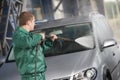 Worker cleaning car with pressured water