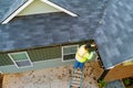 A worker is cleaning clogs in roof gutter drain by picking up dirt, debris, fallen leaves