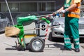 Worker of cleaning company in green uniform with garbage bin.