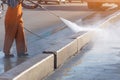 Worker cleaning driveway with gasoline high pressure washer splashing the dirt, asphalt road border. High pressure cleaning Royalty Free Stock Photo