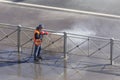 Worker cleaning driveway with gasoline high pressure washer splashing the dirt, asphalt road fence. High pressure cleaning Royalty Free Stock Photo