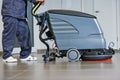 Worker cleaning floor with machine