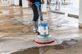 Worker cleaning sand wash exterior walkway using polishing machine and chemical or acid