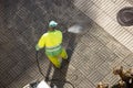 Worker cleaning a street sidewalk with high pressure water jet machine on sunny day