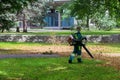 Worker is cleaning up in the city park using leaf blower tool