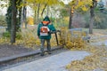 Worker is cleaning up fallen leaves with backpack blower Royalty Free Stock Photo