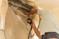 Worker cleaning wall air conditioner with high pressure water jet pump at home.