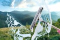 Worker cleaning window with squeegee, closeup. View through clear glass on beautiful mountains Royalty Free Stock Photo