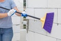 A worker cleans dust with a broom from the wall of a gas block