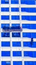 A worker cleans windows on a tall skyscraper office building Royalty Free Stock Photo