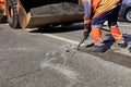 A worker clears a piece of asphalt with a pneumatic jackhammer in road construction