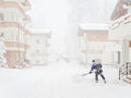 A worker clears snow among cottages on a foggy day during a blizzard