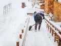 A worker clears snow from a descent from a house during a heavy snowfall