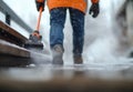 A worker clears snow and ice from outdoor steps using a handheld snow removal tool during a winter storm Royalty Free Stock Photo