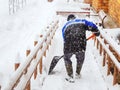 A worker clears snow from the porch of a house during heavy snowfall