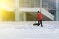 A worker clears snow after a snowstorm in front of a large office building