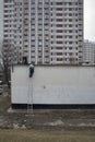 Worker climbed the stairs on the building. In the background is a block house