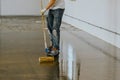 Worker, coating floor with self-leveling epoxy resin in industrial deposit