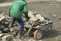 Worker collects stones in cart. Construction debris in garden cart