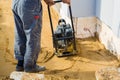 worker compresses sand in blind area around building with special working tool & x28;tamping machine or vibratory plate Royalty Free Stock Photo