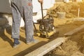 worker compresses sand in blind area around building with special working tool & x28;tamping machine or vibratory plate Royalty Free Stock Photo