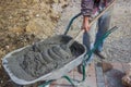 Worker with concrete mortar in wheelbarrow