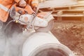 worker at the construction site cutting a concrete drainage pipe with a petrol concrete saw. Builder covered in a hazardous dust Royalty Free Stock Photo