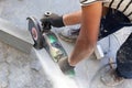 Worker at the construction site saws a piece of concrete curb with angle grinder, circular electric saw, tool in the hands of man