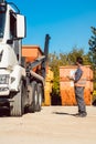 Worker on construction site unloading container for waste from truck Royalty Free Stock Photo