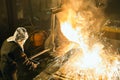 Worker controlling metal melting in furnaces. Workers operates at the metallurgical plant. The liquid metal is poured Royalty Free Stock Photo