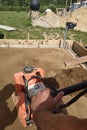 The worker controls the vibrating plate at the construction site, heavy manual construction equipment, pressing and compaction of Royalty Free Stock Photo