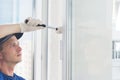 Worker corrects the window frame with a rubber hammer