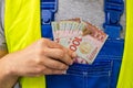 Worker counting his earnings, New Zealand money, Concept of wages and labor costs in industry