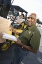 Worker Counting Wooden Planks With Man Driving Forktruck In The Background Royalty Free Stock Photo