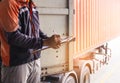 Worker courier holding clipboard checklist checklist to load shipment into a truck container.