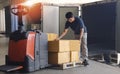 Worker Courier Lifting Package Boxes Stack on Pallet. Cargo Loading at Dock Warehouse. Shipment Supply Chain. Warehouse Logistics
