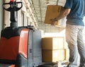 Worker courier lifting shipments boxes at the warehouse.