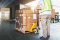 Worker Courier Using Hand Pallet Jack Unloading Package Boxes into Cargo Container. Delivery service. Truck Loading Dock Warehouse Royalty Free Stock Photo