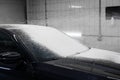 Worker covering automobile with foam at car wash.