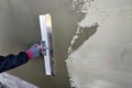 Worker covering insulated wall with solution of glue over plastered styrofoam insulation