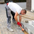 A worker creates a terrace of concrete paving stones.