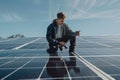A worker crouches on a large solar panel installation under a clear blue sky Royalty Free Stock Photo