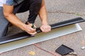 Worker cuts aluminum rain gutters to required size after bending them using a machine tool Royalty Free Stock Photo