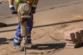 A worker cuts asphalt with an automatic hammer